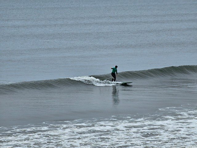 Longboarder riding a knee high wave in front of the shop